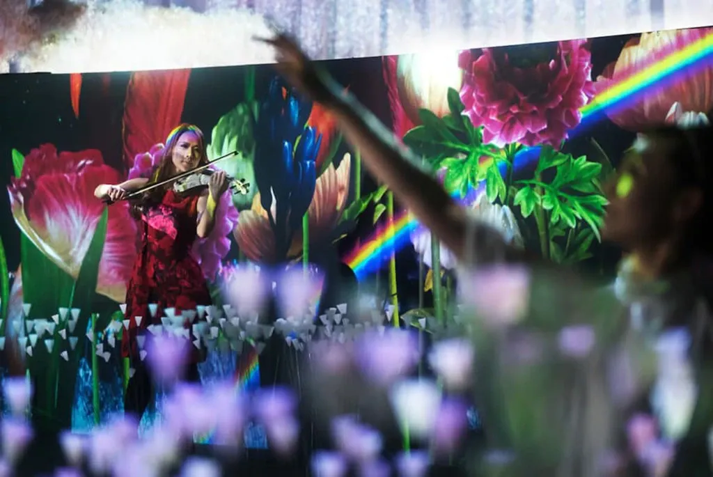 花々の映像に囲まれて演奏するFLOWERS by NAKEDのバイオリニスト
