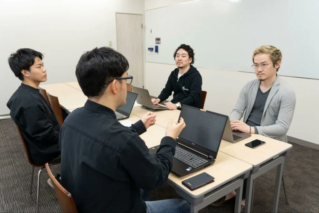 ノートパソコンを囲んで話すLive2Dとgrasysの担当者